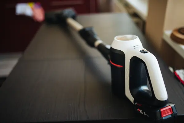Cordless stick vacuum lying on a kitchen counter with its lithium-ion battery pack visible